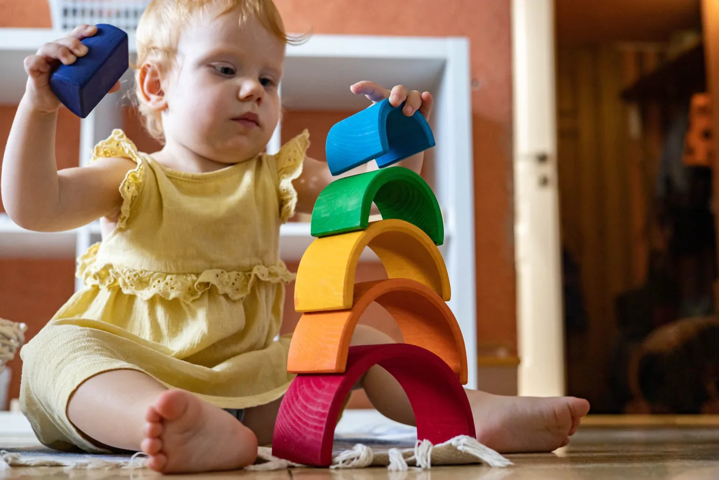 Petite fille empile son Arc en ciel Montessori