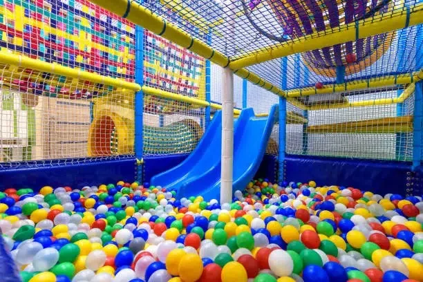 Terrain de jeu pour enfants à l'intérieur. Un exemple de parcours de motricité. Vue panoramique de l'intérieur de la piscine sèche avec des balles colorées et un toboggan.