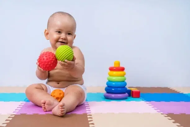 Un jeune enfant joue avec des balles en caoutchouc pour développer la motricité de ses mains.