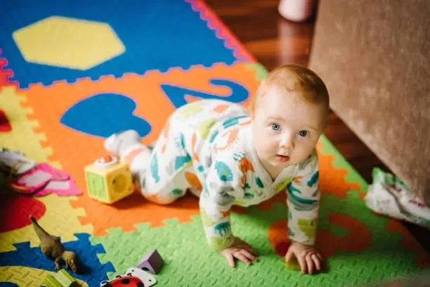 Un bébé rampant sur son joli tapis de motricité
